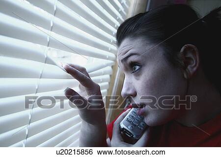 Stock Photograph - Teenage girl on the phone, looking out the window. Fotosearch