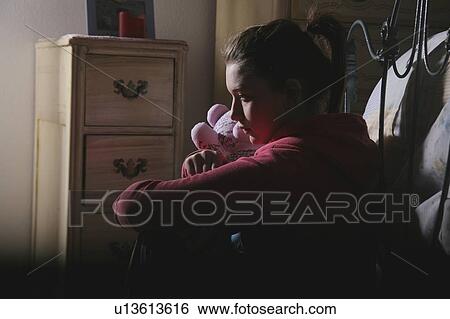 Stock Photograph - Teenage girl sitting in room with teddy bear. Fotosearch