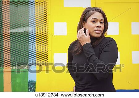 Woman in black standing in front of yellow wall View Large Photo Image Picture - Woman in black standing in front of yellow wall. Fotosearch