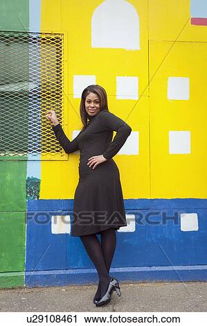Stock Image - Woman standing in front of a city mural. Fotosearch