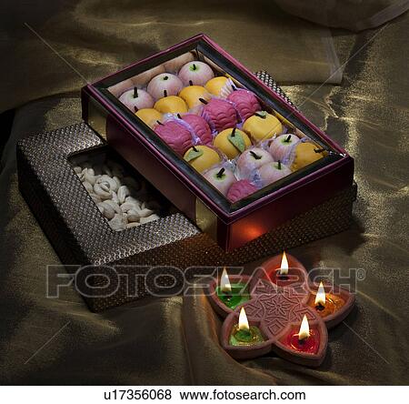 Stock Photo - Box of sweets and nuts with diyas. Fotosearch