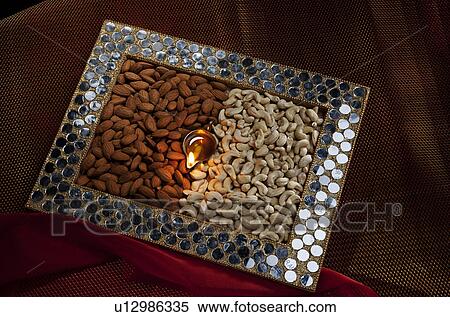 Stock Photography - Box with different nuts and a diya. Fotosearch
