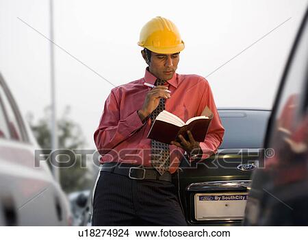 Engineer looking at a book View Large Photo Image Picture - Engineer looking at a book. Fotosearch