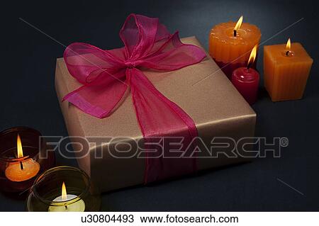 Stock Image - Gift surrounded by candles. Fotosearch