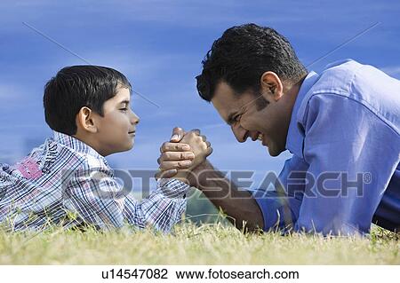 Stock Image - Hand wrestling between son and father. Fotosearch