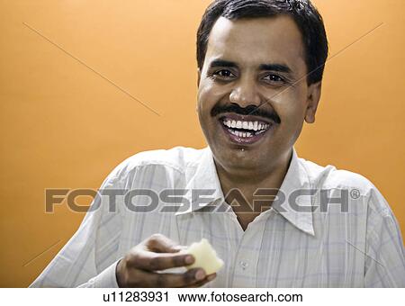 Stock Image - Man eating a sweet. Fotosearch