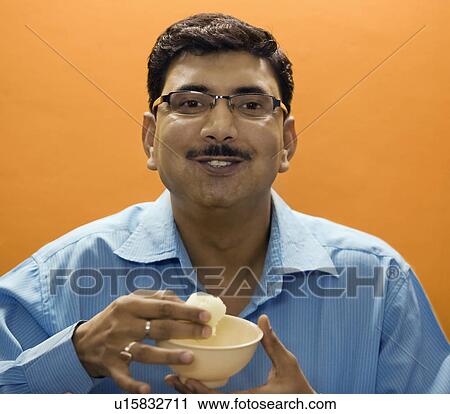 Stock Image - Man eating a sweet. Fotosearch
