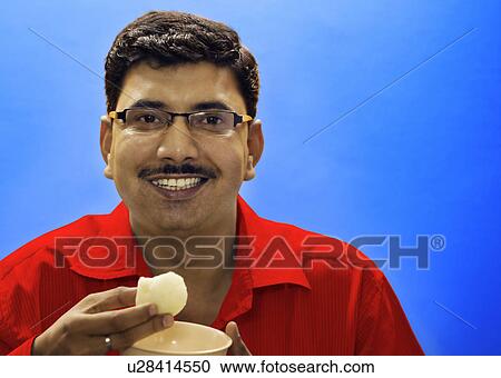 Stock Image - Man eating a sweet. Fotosearch