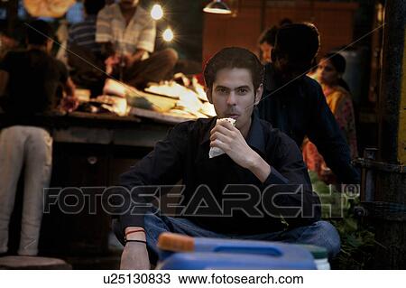 Stock Image - Man eating street food. Fotosearch