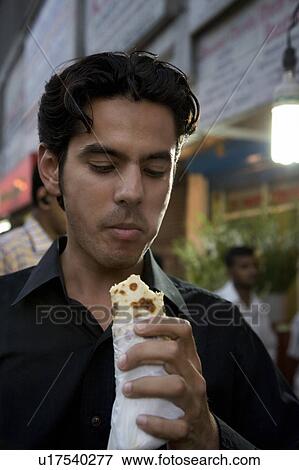 Stock Photo - Man eating street food. Fotosearch