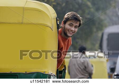 Stock Image - Man looking out of an autorickshaw. Fotosearch