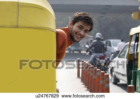 Stock Photo - Man looking out of an autorickshaw. Fotosearch