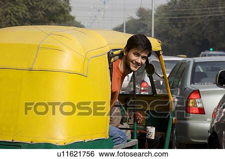 Stock Photograph - Man looking out of an autorickshaw. Fotosearch