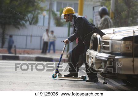 Man on a toy scooter View Large Photo Image Stock Photograph - Man on a toy scooter. Fotosearch