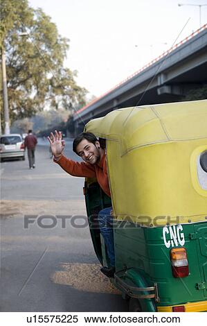 Stock Photography - Man waving from an autorickshaw. Fotosearch