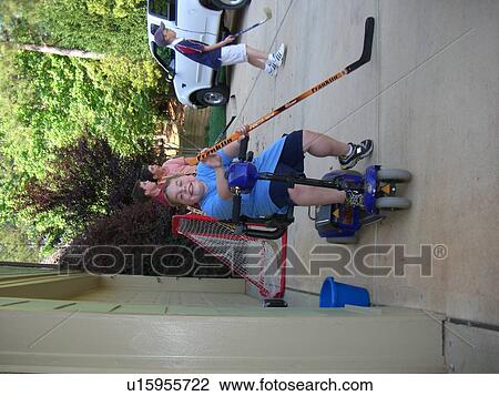 Stock Image - A boy, with Duchene Muscular Dystrophy, plays street hockey at a friend's house.. Fotosearch