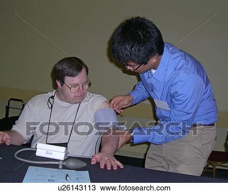 Stock Image - A man teaches a man how to read his blood pressure.. Fotosearch