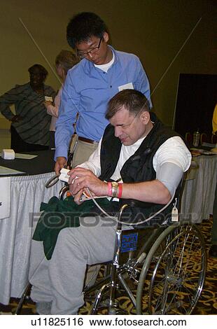 Stock Photograph - A man teaches a man how to read his blood pressure.. Fotosearch