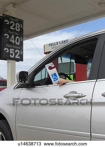 Stock Image - A woman holds a handicap parking permit.. Fotosearch