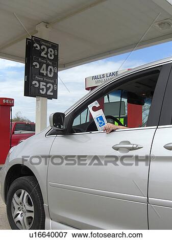 Stock Photo - A woman holds a handicap parking permit.. Fotosearch