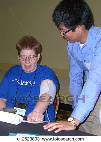 Stock Image - A woman waits for her blood pressure.. Fotosearch