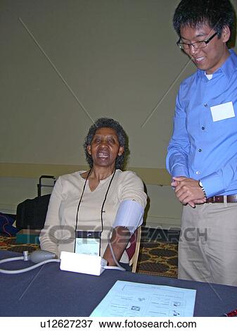 Stock Photo - A woman waits for her blood pressure.. Fotosearch