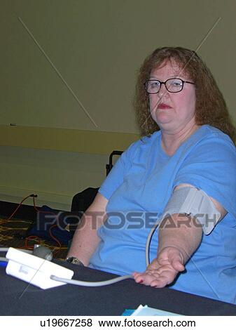 Stock Photo - A woman waits for her blood pressure.. Fotosearch