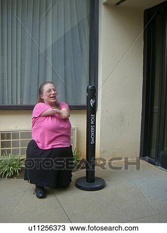 A woman, who is of short stature, enjoys a cigarette. View Large Photo Image Stock Image - A woman, who is of short stature, enjoys a cigarette.. Fotosearch