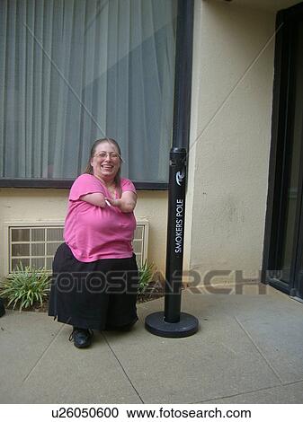 Stock Image - A woman, who is of short stature, enjoys a cigarette.. Fotosearch