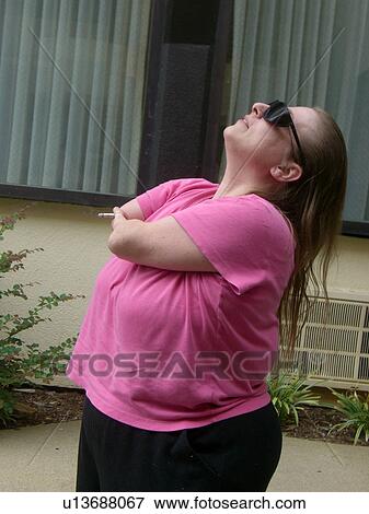 A woman, who is of short stature, enjoys a cigarette. View Large Photo Image Stock Photo - A woman, who is of short stature, enjoys a cigarette.. Fotosearch