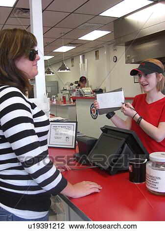 Stock Image - A woman, who is visually impaired, pays for her food after eating at her favorite restaurant.. Fotosearch