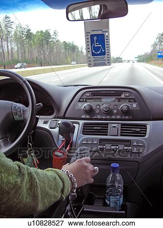 Stock Photo - A woman, who uses a handicap parking permit, drives her van down the highway.. Fotosearch