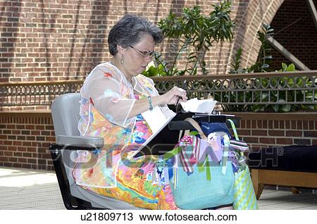 Stock Image - A woman, who uses a wheelchair, prepares for a meeting.. Fotosearch