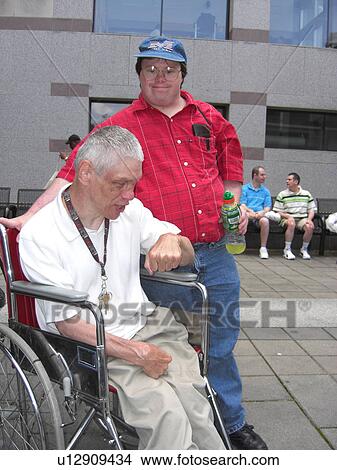 Picture - Two friends, one who uses a wheelchair, hang out at a rally.. Fotosearch