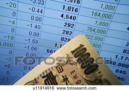 Stock Photograph - 10, 100 Yen bill in front of computer screen displaying financial spreadsheet. Fotosearch