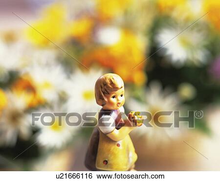 Stock Photograph - A ceramic figure of a little girl in front of a bouquet of flowers. Fotosearch