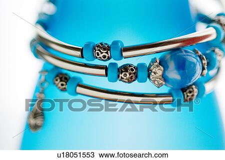 Stock Image - Blue and silver beaded necklace wrapped around a blue bottle. Fotosearch