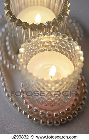 Stock Photo - Candles in glass holders and a pearl necklace. Fotosearch
