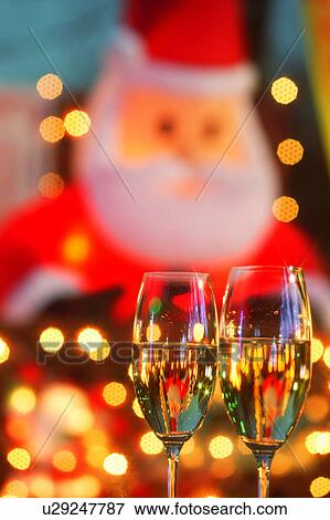 Stock Photo - Champagne glasses toasting Christmas in front of Christmas decorations. Fotosearch