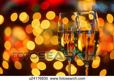 Stock Photography - Champagne glasses toasting Christmas in front of Christmas lights. Fotosearch
