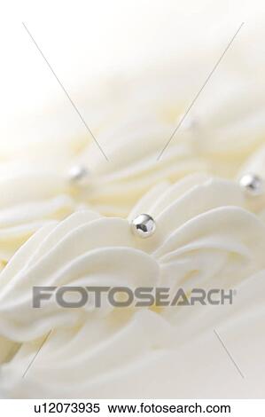Stock Photography - Close up of cream decorations, white background. Fotosearch