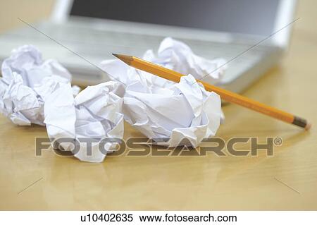 Stock Photography - Crumpled balls of paper on desk next to laptop. Fotosearch