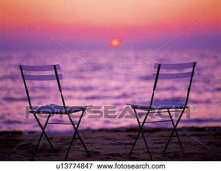 Empty chairs on the beach by sea at sunset. View Large Photo Image Stock Photo - Empty chairs on the beach by sea at sunset.. Fotosearch