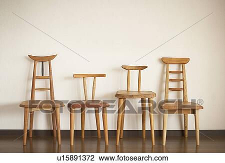 Stock Image - Four wooden chairs against white wall. Fotosearch