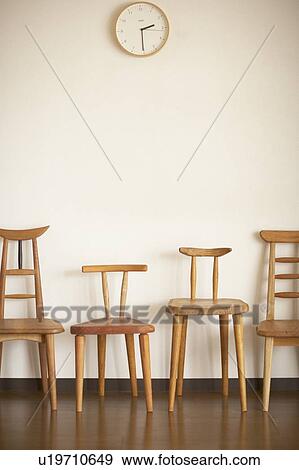 Stock Photo - Four wooden chairs against white wall. Fotosearch