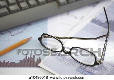 Stock Photo - Glasses resting on financial documents on an office desk. Fotosearch