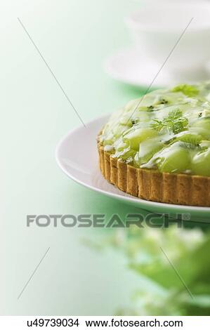 Picture - Muscat grape and kiwi tart on plate, green background. Fotosearch