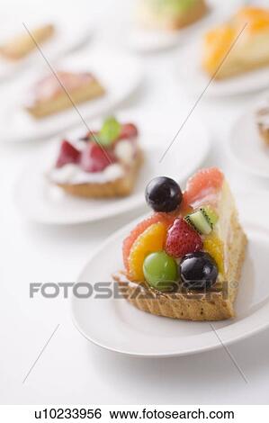 Stock Photograph - Pieces of tart on plates, close up, white background. Fotosearch