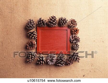 Picture - Pine cones around a red piece of wood. Fotosearch