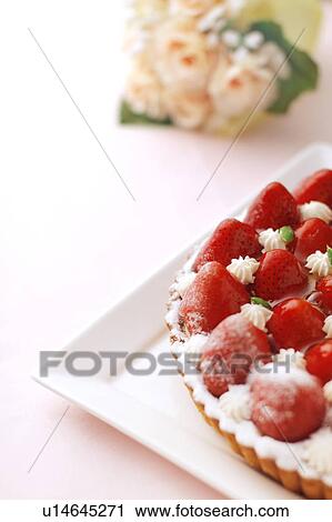 Stock Image - Plate of strawberry tart and flower bouquet, white background. Fotosearch